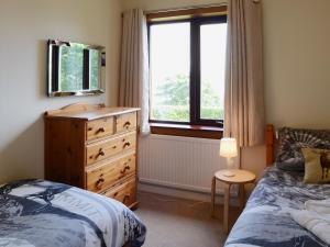 a bedroom with a bed and a dresser and a window at Deo Na Mara in Midtown Brae