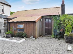 a wooden shed with a door in a yard at Port Righ Cottage in Carradale +3 photos