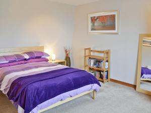 a bedroom with a purple bed and a book shelf at Bayview in Collieston