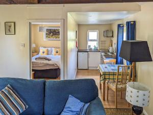 a living room with a blue couch and a bedroom at Port Righ Cottage in Carradale