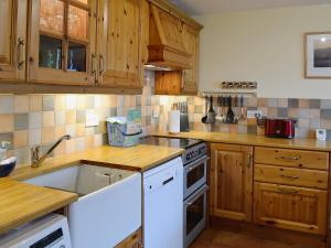 a kitchen with wooden cabinets and white appliances at Bayview in Collieston