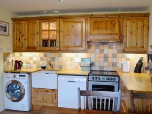 a kitchen with wooden cabinets and a white dishwasher at Bayview in Collieston