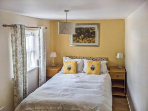 a bedroom with a bed with yellow walls and a window at Port Righ Cottage in Carradale