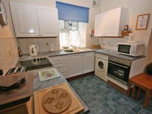 a kitchen with white cabinets and a stove top oven at Lochview Barn in Strathyre