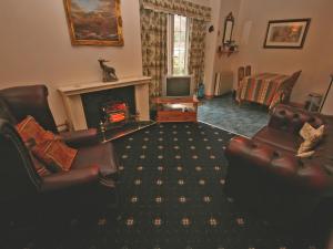 a living room with two leather chairs and a fireplace at Lochview Barn in Strathyre