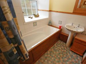 a bathroom with a bath tub and a sink at Lochview Barn in Strathyre +3 photos