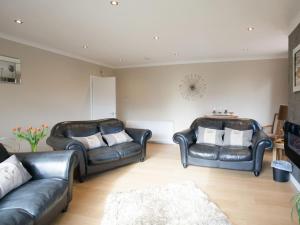 a living room with two leather chairs and a couch at Strone Farm House in Torcastle