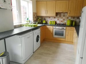 a kitchen with wooden cabinets and a white dishwasher at Belle Isle Cottage in Haworth