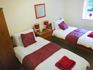 a bedroom with two beds and a mirror at Belle Isle Cottage in Haworth