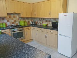 a kitchen with wooden cabinets and a white refrigerator at Belle Isle Cottage in Haworth