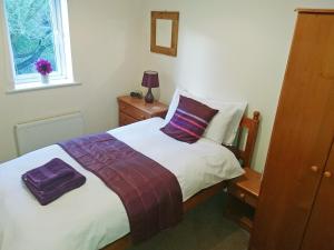 a bedroom with a bed with purple pillows and a window at Belle Isle Cottage in Haworth +4 photos