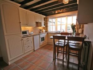 a kitchen with white cabinets and a table and chairs at Granary Cottage Whittingham in Whittingham
