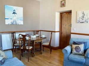 a dining room with a table and a blue couch at Granary Cottage Whittingham in Whittingham