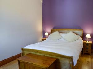 a bedroom with a bed and a purple wall at Granary Cottage Whittingham in Whittingham +10 photos