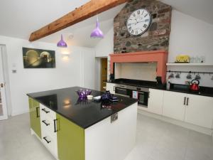 a kitchen with a clock on a stone wall at Dornock Brow Cottage in Dornock
