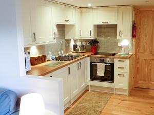 a kitchen with white cabinets and a stove top oven at Crosskeys Cottage in Shandon