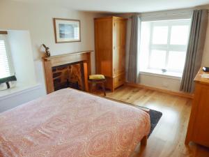 a bedroom with a bed and a fireplace at Crosskeys Cottage in Shandon