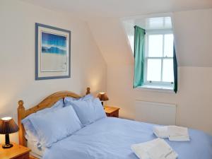 a bedroom with a blue bed and a window at Sanctuary Cottage in Applecross +10 photos