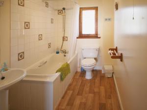 a bathroom with a toilet and a tub and a sink at Kildonan in Laide +8 photos