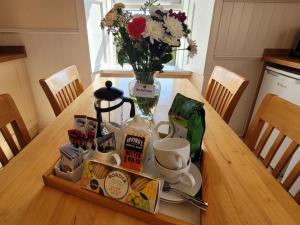 a wooden table with a vase of flowers and a vase of coffee cups at Palmallet Cottage in Whithorn