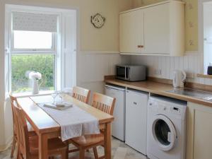a kitchen with a table with chairs and a microwave at Palmallet Cottage in Whithorn