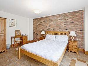 a bedroom with a bed and a brick wall at Cobble Cottage - W41945 in Filey
