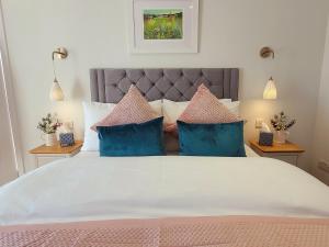 a bedroom with a large bed with blue and pink pillows at Palmallet Cottage in Whithorn +21 photos