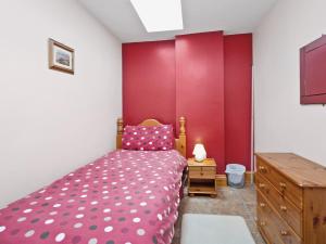 a bedroom with a bed and a red wall at Cobble Cottage - W41945 in Filey