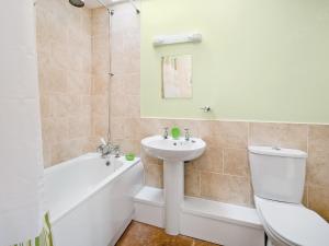 a bathroom with a sink and a toilet and a bath tub at Cobble Cottage - W41945 in Filey