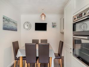 a dining room with a table and chairs and a clock at Chaucer Rise in Exmouth