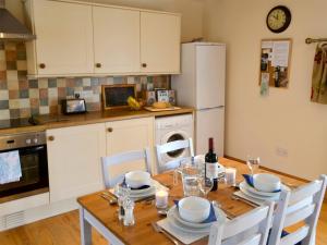 a kitchen with a wooden table with chairs and a refrigerator at Knoppingsholme Stable in Greenhaugh