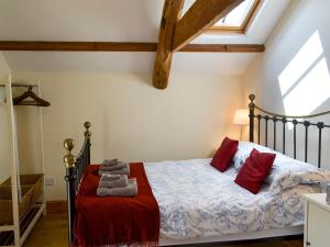 a bedroom with a bed with red pillows at Knoppingsholme Stable in Greenhaugh