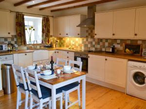 a kitchen with a table with chairs and a sink at Knoppingsholme Stable in Greenhaugh