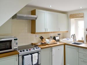 a kitchen with white cabinets and a microwave at The Smithy in Ovingham