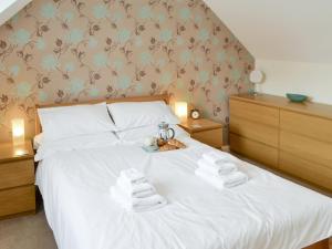 a bedroom with a white bed with towels on it at The Smithy in Ovingham +4 photos