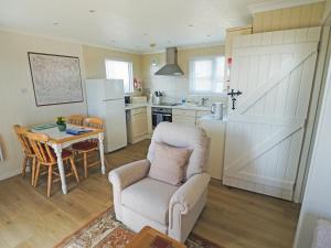 a kitchen with a table and a chair and a kitchen with a refrigerator at Ash Lodge in Nawton
