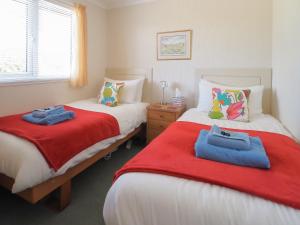 a bedroom with two beds with red and blue towels on them at Ash Lodge in Nawton +3 photos