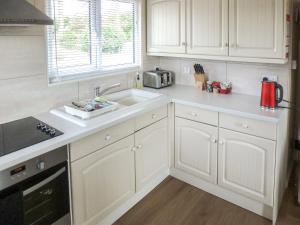 a kitchen with white cabinets and a sink at Ash Lodge in Nawton