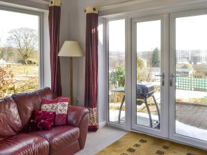 a living room with a leather couch and sliding glass doors at Heatherlea in Otterburn