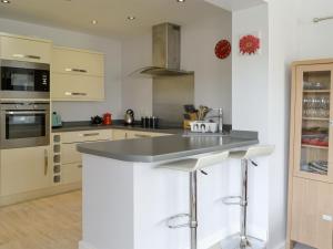 a kitchen with white cabinets and a gray counter top at Heatherlea in Otterburn +15 photos