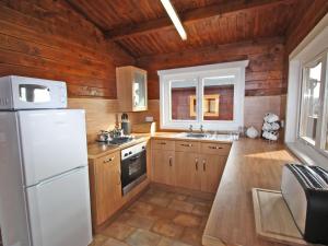 a kitchen with a white refrigerator and wooden walls at White Springs - Lake View in Llanedy