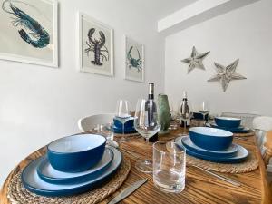 a dining room table with blue dishes and wine glasses at Surf Cottage in Cromer