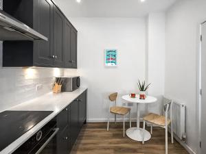 a kitchen with black cabinets and a table with chairs at Surf Cottage in Cromer
