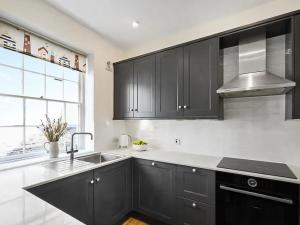 a kitchen with black cabinets and a sink at Surf Cottage in Cromer