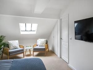 a bedroom with two chairs and a tv and a bed at Surf Cottage in Cromer +11 photos