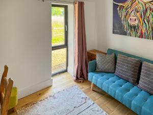 a living room with a blue couch in front of a window at Fernhill Stables in Sevenoaks +6 photos