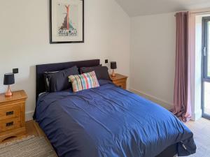 a bedroom with a blue bed and a window at Fernhill Stables in Sevenoaks