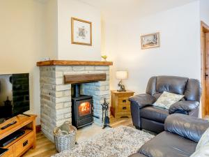 a living room with a fireplace and a leather chair at Shepherd's Nook - Uk32388 in Dunford Bridge