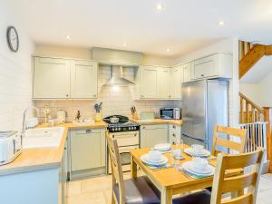 a kitchen with a table and a kitchen with a stove and refrigerator at Shepherd's Nook - Uk32388 in Dunford Bridge +18 photos