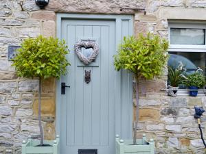 a stone house with a white door with a wreath at The Old Cobblers Cottage in Bakewell +3 photos
